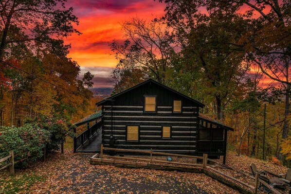 Our rustic hand-hewn log cabin stands tall amidst a tranquil forest in Pigeon Forge. The warm glow of the setting sun casts a golden hue on the cabin's walls, inviting you to cozy up inside for the night.