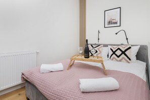 A bright bedroom with a pink bedspread and minimal decorations.
