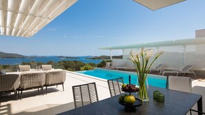 Blick auf das Meer und die Insel Školjić von der Außenterrasse der luxuriösen Villa Murter Glory mit Tisch und Möbeln zum Entspannen am beheizten Pool