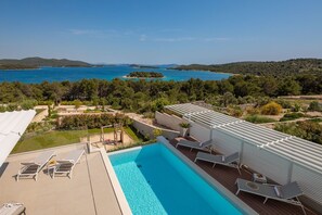 Blick auf die Terrasse mit Swimmingpool und Vordach, den Hof der luxuriösen Villa Muerte Glory und den Blick auf das Meer und die Insel Školjić