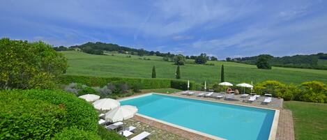 La amplia y equipada piscina compartida rodeada de la típica campiña toscana.