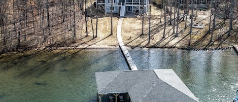 Aerial view. Boathouse with house in the back. Natural sandy beach.