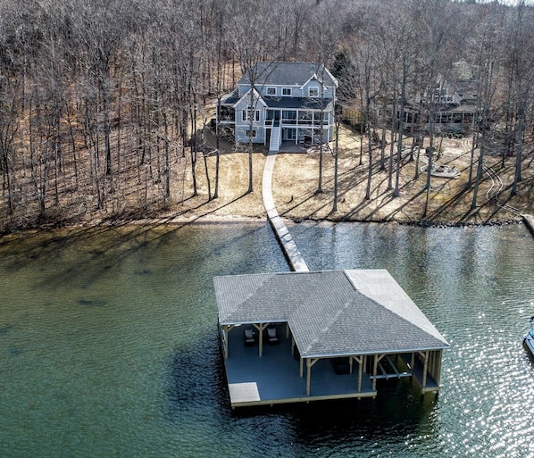 Aerial view. Boathouse with house in the back. Natural sandy beach.