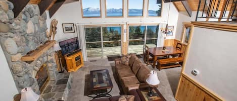 This three-bedroom cabin is filled with charming cabin decor, high ceilings with exposed wood beams, and an open living space featuring soaring windows overlooking Lake Tahoe.
