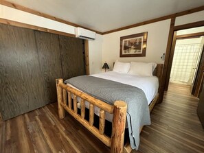 The home has two quiet bedrooms for a peaceful night's rest such as this one with a queen-size bed in a log frame with a large closet.