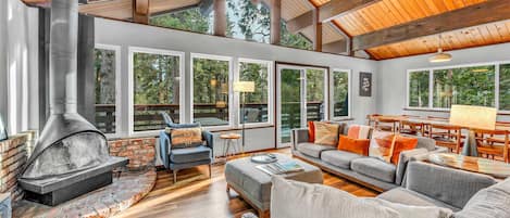 Living Room: 2 couches, 1 chair, wood-burning fireplace, 55” Smart TV, access to deck