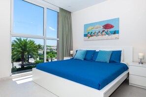 Vibrant master bedroom with flatscreen TV and a transparent glass window.