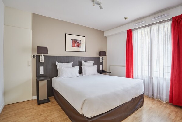 Warm-toned bedroom with red accents and large windows, offering a cozy space to unwind.
