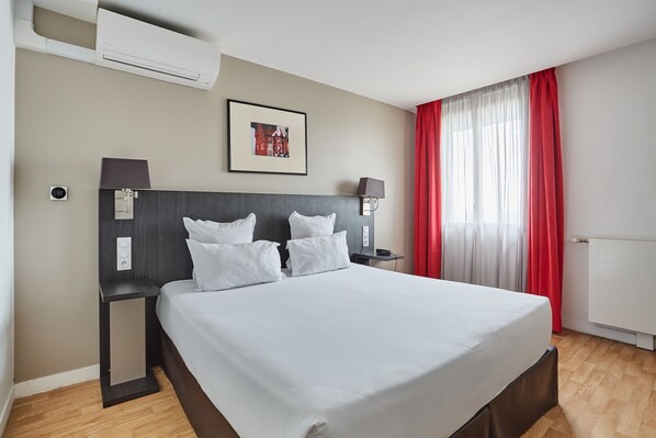 Studio sleeping area with red accent curtains and a cozy double bed, ideal for a restful city break.
