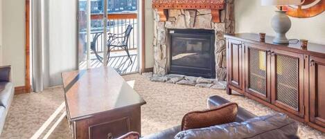 The charming living space offers a spacious common area for relaxing with two large couches, a 65” TV,  a lovely stone gas fireplace, and views out the balcony doors over Canyons Ski Resort.
