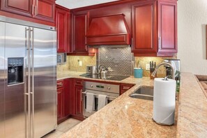 The kitchen features stainless steel appliances including a large stainless steel fridge/freezer for ample food and beverage storage space.