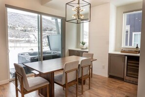 The dining area is a light-filled space with a wood dining table with seating for six and a sliding glass door leading out to a second outdoor space that features a small patio area with a private hot tub.