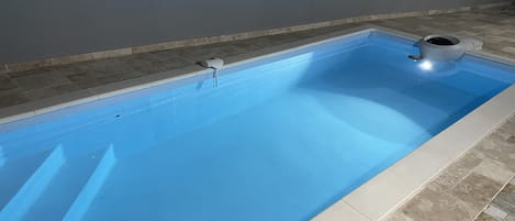 Piscine bâchée et sous alarme avec belle plage carrelée protégée par un kiosque