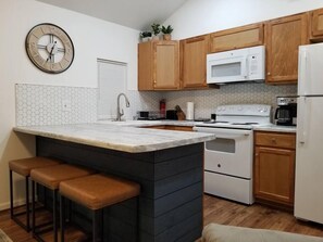 Kitchen and bar area; additional barstool in unit for dining at bar.