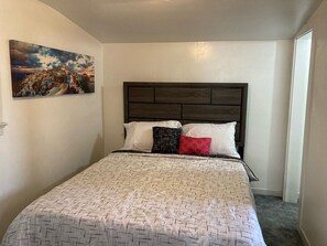 small bedroom with queen bed, bathroom and closet