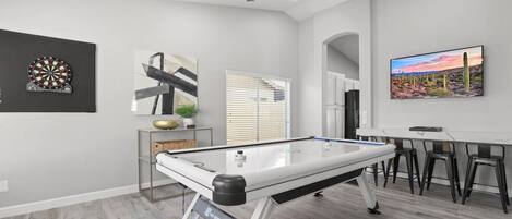 Entertainment room with an air hockey, dart, and a flat-screen TV