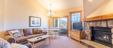 Living area with gas fireplace, flat screen TV, queen size sleeper sofa, vaulted ceiling and access to the private balcony.