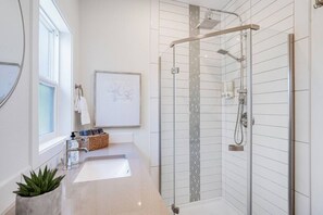 Walk-in luxury rain shower, quartz counters, and toiletries provided.