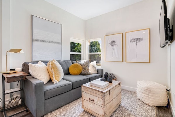 Cozy living area with queen sleeper sofa, smart TV, and convertible side table/desk.