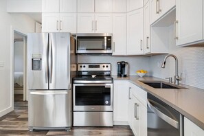 Quartz counters, penny tile backsplash, stainless steel appliances, and a fully stocked kitchen for all your cooking needs.