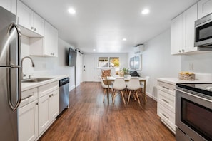 Fully stocked kitchen near dining and living areas with AC and TV.