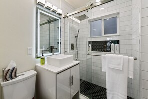 Stylish bathroom with walk-in shower and backlit mirror. 