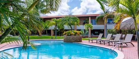 Refreshing tropical Pool Area of the Apartment in Oranjestad Aruba - Relax by the shimmering poolside oasis - Comfort at its best - Enjoy leisurely moments in inviting pool area - Palm trees and tropical plants enhance the vacation feel