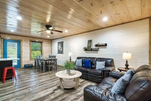 The main living area includes a 55-inch smart tv, sleeper sofa, loveseat, island with two bar stools, and a table that seats six.