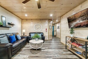 The main living area includes a 55-inch smart tv, sleeper sofa, loveseat, island with two bar stools, and a table that seats six.