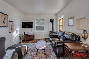 As you walk in the sun filled living room features a Smart TV, cozy seating & a classic wood burning stove