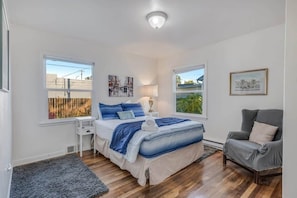 Bedroom one has lots of windows creating a bright & airy space with a queen bed & added seating