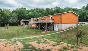 Back of home with steps and deck and volleyball area. 