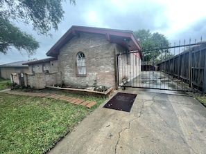 Driveway view with gate which opens both ways, into driveway and out.  