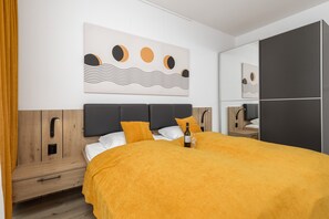 A bedroom with a yellow bedspread, minimalist decor, and a wardrobe.