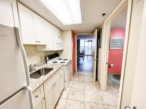 Kitchen wtih stove, microwave, keurig and fridge.