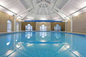 An indoor pool under a vaulted ceiling, offering a serene spot for a swim in any weather.