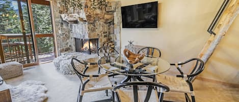 Spacious living room with soaring high ceilings, fireplace, and a dining table