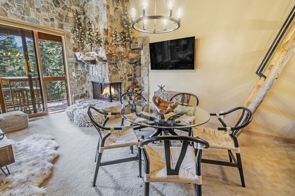 Spacious living room with soaring high ceilings, fireplace, and a dining table