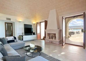 Living room with large sectional, TV, fireplace and French doors to pool. 