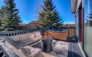 Comfy sectional couch next to fire bowl and hot tub.