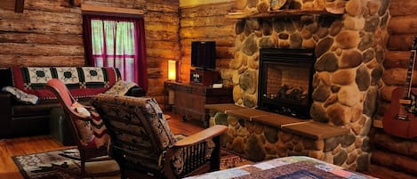 Main Log Room w/ Queen size bed, couch, antique rockers, TV and gas fireplace