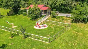 Drone image, fenced in areas around cottage, porch with gas grill, fire pit and doggy play areas with seesaw, sandbox and sniffary route surrounded by fruit trees.