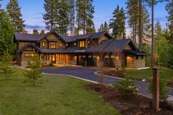Luxury mountain lodge with grand timber architecture and glowing twilight curb appeal.