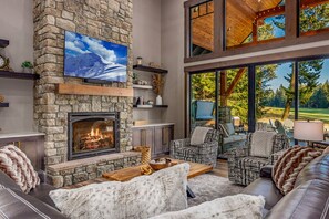 Luxe lodge living with soaring stone gas fireplace and floor-to-ceiling glass window
