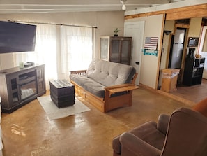 Living Room with Full Size Futon Bed and Leather Armchair, TV & Fireplace Heater