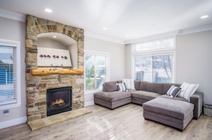 Experience the cozy living room, outfitted with plush seating, an expansive smart TV, and sliding patio doors that frame the breathtaking mountain vistas.