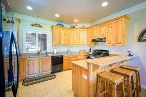 The gourmet kitchen features a breakfast bar with seating for three and is equipped with appliances, including a microwave, gas stove, and spacious refrigerator.