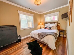 Queen Room 1 with lots of natural light, tv, dresser and closet, and premium mattresses