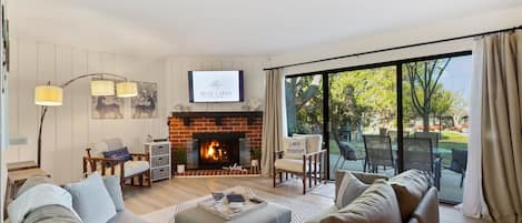 Enjoy the gas fireplace while relaxing in the open great room with a Smart TV,  large sliders to walk out to patio, and peek thru window to kitchen!