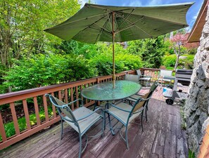 Deck has a dining table and propane grill